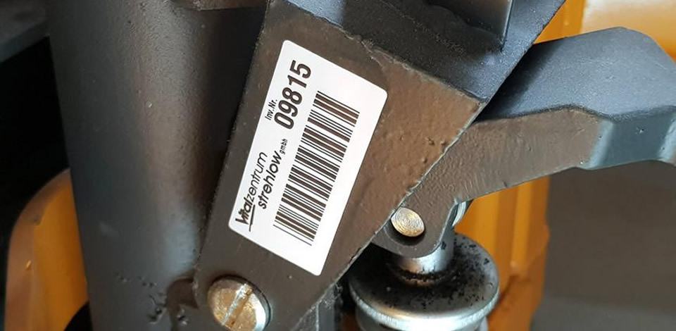Ein Inventarschild, das einen Hubwagen mit Inventarnummer und Barcode kennezichnet